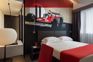 a bedroom with a bed with a race car on the wall at Hotel Maranello Village in Maranello