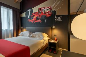 a bedroom with a bed and a poster of a race car at Hotel Maranello Village in Maranello