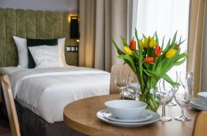 a hotel room with a bed and a table with flowers at Verde Apartments CENTRUM in Koszalin