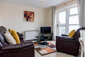 a living room with two couches and a tv at Marine Court Sea View in Bundoran