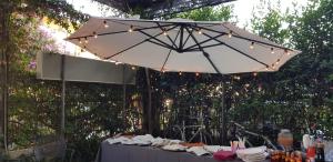 una mesa con sombrilla blanca y luces en Hotel Eros, en Lido di Camaiore