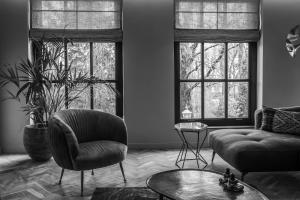 a living room with a couch and a chair and two windows at Parkhotel Abcoude in Abcoude
