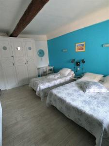two beds in a room with blue walls at Hôtel-restaurant le Palais in Apt