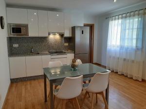 a kitchen with a table and chairs and a kitchen with white cabinets at Casa Galipendre in A Estrada