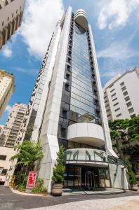 un grand bâtiment blanc avec une façade en verre dans l'établissement Apart Alameda Lorena, à São Paulo
