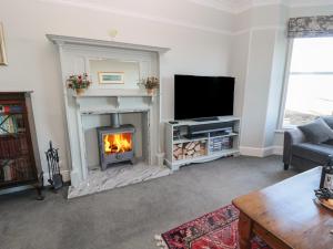a living room with a fireplace and a television at Whinstones at 4 The Villas in Alnwick
