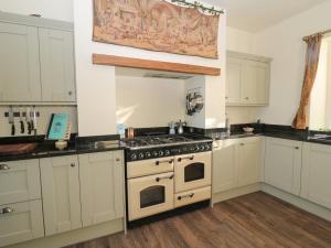 a kitchen with white cabinets and a stove top oven at Whinstones at 4 The Villas in Alnwick