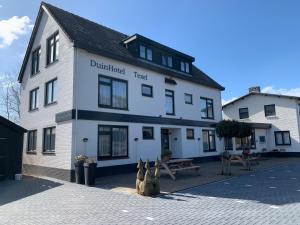 a white building with some statues in front of it at DuinHotel Texel in De Koog