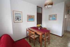 Habitación con mesa, sillas y sofá rojo. en Villa Tatiana appartamento en Rosolina Mare