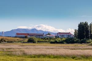 una casa en un campo con montañas en el fondo en Hostería El Galpón Del Glaciar en El Calafate