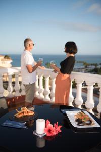 a man and woman standing on a balcony holding wine glasses at Casa Roja in Costa Calma