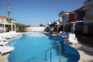 a large swimming pool with white lounge chairs around it at Cundavilla Hotel & Suites in Ayvalık
