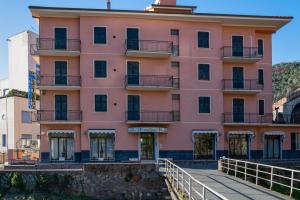 ein rosafarbenes Gebäude mit einem Gehweg davor in der Unterkunft Hotel Residence Paradiso in Moneglia