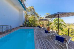 a pool on a deck with chairs and umbrellas at La Maison Blanche in Manuel Antonio