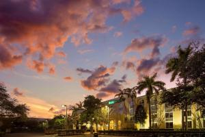 um edifício com palmeiras e um céu nublado em La Quinta Inn & Suites by Wyndham Sunrise em Sunrise