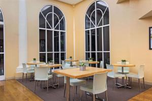 a restaurant with tables and chairs and large windows at La Quinta Inn & Suites by Wyndham Sunrise in Sunrise