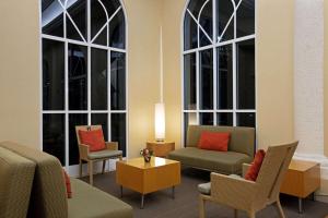 a living room with two large windows and a couch and chairs at La Quinta Inn & Suites by Wyndham Sunrise in Sunrise