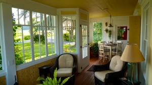 a screened in porch with two chairs and a table at Enfield Manor Bed&Breakfast and Vacation Rental in Newfield
