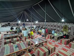 a group of people sitting at tables in a tent at Alsarmadi Desert Camp in Shāhiq