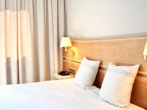 ein Hotelzimmer mit einem Bett mit zwei Kissen in der Unterkunft Maison Jenny Hotel Restaurant & Spa in Hagenthal-le-Bas
