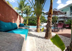 a patio with a couch and palm trees next to a pool at Pousada Toca da Praia in Maresias