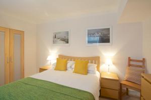 a bedroom with a bed with yellow pillows and two lamps at Beach View in St Ives