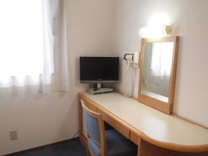 a room with a desk with a monitor and a mirror at Hotel Green Mark in Sendai