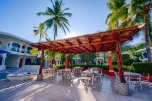 um pátio com mesas, cadeiras e palmeiras em Hotel Costa Azul em Acapulco