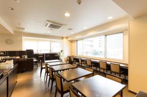 a restaurant with wooden tables and chairs and a large window at Dormy Inn Express Mikawaanjo in Anjomachi