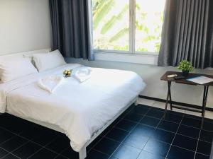 a bedroom with a white bed with a window at NK Guesthouse 2 in Bangkok