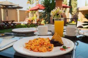 een bord eten op een tafel met een glas sinaasappelsap bij Capital O La Huerta Golf & Hotel in Cholula