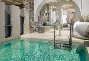 
a swimming pool with a tub and a stone wall at Kensho Ornos in Ornos
