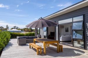 a patio with a wooden table and an umbrella at BACCHUS in Martinborough 