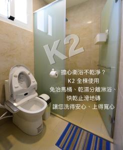 a bathroom with a toilet with a sign on the wall at K2 Hostel in Taitung City