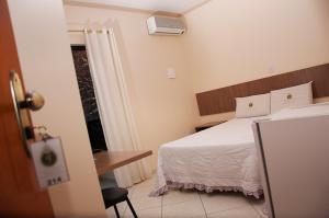 Cette chambre comprend un lit, un bureau et une fenêtre. dans l'établissement Imperial Hotel, à Santa Bárbara
