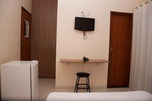a room with a desk and a television on the wall at Imperial Hotel in Santa Bárbara +8 photos