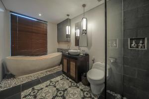 a bathroom with a tub and a toilet and a sink at Gaing Mas Jimbaran Villas by Gaing Mas Group in Jimbaran