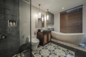 a bathroom with a tub and a toilet and a sink at Gaing Mas Jimbaran Villas by Gaing Mas Group in Jimbaran