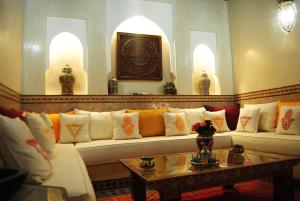 a living room with a white couch with colorful pillows at Riad Gallery 49 in Marrakech
