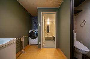 a bathroom with a toilet and a tv in it at Residence Hotel Takayama Station in Takayama