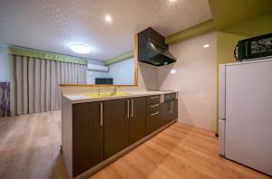 a kitchen with a refrigerator, stove, sink and cabinets at Residence Hotel Takayama Station in Takayama