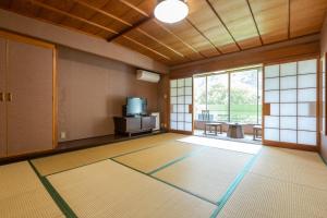a room with a large room with a door and a television at Tabist Spa Yubara Okayama Yubaraonsen in Maniwa