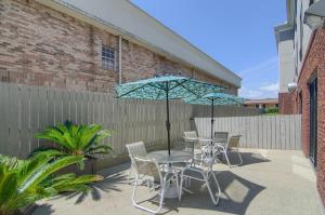 a patio with a table and chairs and an umbrella at Comfort Suites Mobile-South Alabama University Area in Mobile