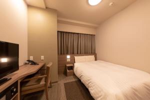 Dormitorio con cama, escritorio y TV en Dormy Inn Premium Fukui Natural Hot Spring en Fukui