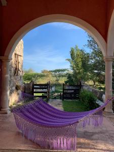 Un arco con una hamaca púrpura en un patio en Hacienda Sacnicte, en Izamal