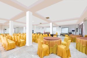 una stanza con tavoli, sedie gialle e schermo di Super OYO 2704 Hotel Transit 2 a Makassar