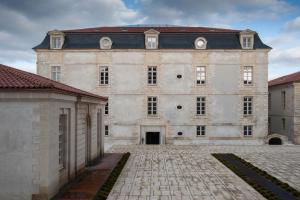 un grand bâtiment en pierre avec un toit rouge dans l'établissement Résidence de l'Arsenal Royal - Meublés de Tourisme, à Rochefort