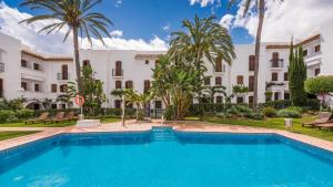 una piscina frente a un edificio con palmeras en Macdonald Villacana Resort, en Estepona