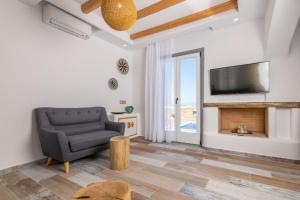 a living room with a chair and a television at NAXIAN SUNSET VILLAS in Naxos Chora