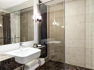 a bathroom with a sink and a glass shower at Metropol Palace, Belgrade in Belgrade